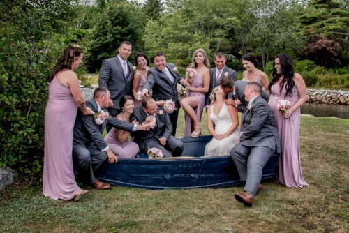 Joyful wedding celebration in Halifax featuring bride, groom, bridesmaids, and groomsmen in scenic garden backdrop. Elegant Halifax wedding photography with bridal party in soft pink and gray attire outdoors.