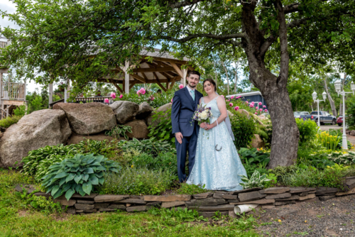 The bride and groom pose for wedding photos in a garden at the Founders House in Annapolis Royal NS.